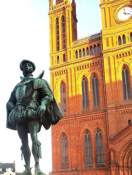 "Wilhelm der Schweiger" vo der Marktkirche. Die Statue von "Wilhelm dem Schweiger" vor einer majestetischen Kirche mit roten Backsteinziegeln im neugotischen Stil.